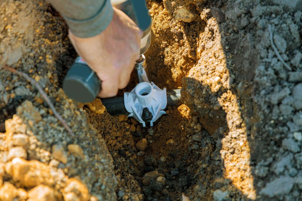 Man using a power tool to repair a residential sprinkler system